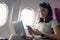 Attractive asian woman passenger of airplane read news from networks via smartphone and wifi on board. tourism traveler
