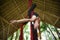 Attractive and athletic aerialist woman hanging from silk fabric doing aerial dancing workout training happy at beautiful hut in