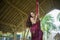 Attractive and athletic aerialist woman hanging from silk fabric doing aerial dancing workout training happy at beautiful hut in