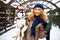 Attractive authentic caucasian woman hugs funny malamute dog wearing santa dear christmas antlers. Curly smiling female