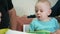 Attractive baby boy draws a pen with his grandparents home on the couch. The boy stares at the animals that drew