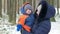 Attractive baby in mother`s arms in the winter. They talk and laugh. Both are dressed in warm blue and orange. The