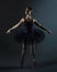 Attractive ballerina poses gracefully in the studio on a black background