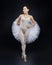 Attractive ballerina poses gracefully in the studio on a black background
