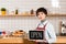 Attractive barista holding signboard with open lettering and looking at camera.