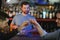 Attractive bartender is smiling and taking order of two men sitting at bar counter in pub