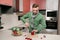 Attractive bearded man with knife in his hand cuts salad of decorated Christmas balls. Concept of preparation for the holiday