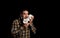 Attractive bearded man in a yellow plaid shirt with a stuffed puppy posing isolated on black background