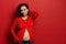 Attractive beautiful pregnant woman, expectant mother, looking at camera, dressed in red shirt, showing her bare belly