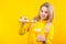 Attractive beautiful young blonde woman in casual sporty clothes pouring orange juice from plastic bottle to glass