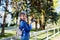 Attractive beautiful young girl holding modern mirror camera in autumn park. Traveller walking in place with yellow leaves on tree