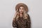 Attractive beautiful young woman in an elegant beige hat in a trendy leopard sweater with curly blond hair