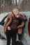 Attractive beautiful young woman in sweater staying next to the car in forest. Winter vacation. Holidays. Smilling