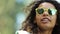 Attractive biracial girl in yellow sunglasses dancing, singing among friends