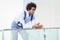 Attractive black businessman with afro hair, resting on a railing of his office building.