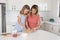 attractive blond 30s woman cooking and baking happy together with sweet adorable mini chef little girl at home modern kitchen