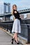 Attractive blond fashion model posing pretty on the pier with Manhattan Bridge on the background.