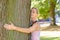 Attractive blond female nature lover hugging tree