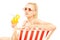 Attractive blond female sitting on a sun lounger and drinking a