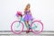 Attractive blonde beauty on colorful bike, decorated with flowers. Spring concept. Beautiful natural woman in elegant pastel dress