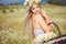 Attractive blonde in chamomile field. Young woman in wreath