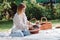 Attractive blonde girl sitting on white blanket in garden with cute welsh corgi puppies in wicker basket.