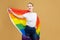 Attractive blonde made posing with a rainbow LGBT flag. photo shoot in the studio on a yellow background