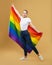 Attractive blonde made posing with a rainbow LGBT flag. photo shoot in the studio on a yellow background