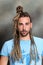 Attractive blonde male model with combination of braids and dreadlocks posing in studio on isolated background.