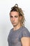 Attractive blonde male model with combination of braids and dreadlocks posing in studio on isolated background.