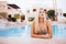 Attractive blonde Slim Woman at the Edge of Beautiful Pool Smiling on camera.