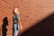 Attractive blonde teen girl in grey striped y-shirt and jeans touching her hair and lookinf at the camera isolated over