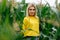 An attractive blonde woman in a yellow tank top walks in a cornfield in summer. Portrait of a beautiful, young, sexy long-haired