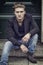 Attractive blue eyed, blond young man sitting on stair steps