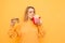 Attractive bright girl with malicious food in her hands on a yellow background, holds in the hands of burger and fries,sniffs