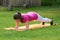 Attractive brown haired girl keeping body in plank parallel to ground on mat.