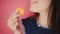 Attractive brunette eats macarons isolated on bright backgrounds