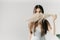 An attractive brunette hides her face behind a fluffy dry branch of a plant on a light gray background. Pampas grass.