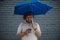 Attractive brunette latin man holding blue umbrella and mobile phone.