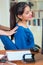 Attractive brunette office woman wearing blue sweater sitting by desk receiving back massage, stress relief concept