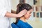 Attractive brunette office woman wearing blue sweater sitting by desk receiving head massage, stress relief concept