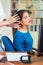 Attractive brunette office woman wearing blue sweater sitting by desk receiving head massage, stress relief concept