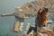 Attractive brunette seen from behind posing while sitting on a stone above the city of Dubrovnik, outlines of the majestic old