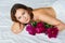 attractive brunette topless woman with a bouquet of peonies on the bed.