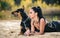 Attractive brunette woman with a doberman lying on the sand