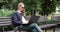 attractive business woman with sunglasses sitting on the bench in park and working on laptop