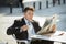 Attractive businessman sitting outdoors having coffee cup for breakfast early morning reading newspaper news looking relaxed