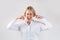 Attractive businesswoman in closing her ears and screaming in anger on light grey studio background