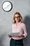 attractive businesswoman in glasses and shirt holding papers in office.