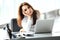 Attractive businesswoman sitting on a desk with laptop in the office.